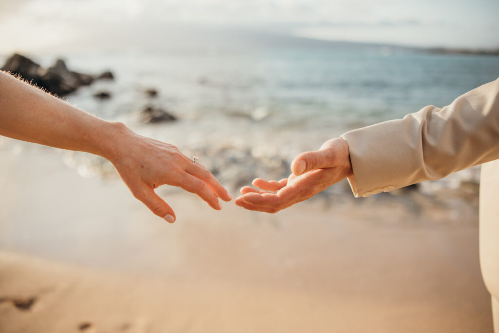 Maui Elopement Photographer captures bride and groom reaching for one another's hands during Hawaii beach wedding