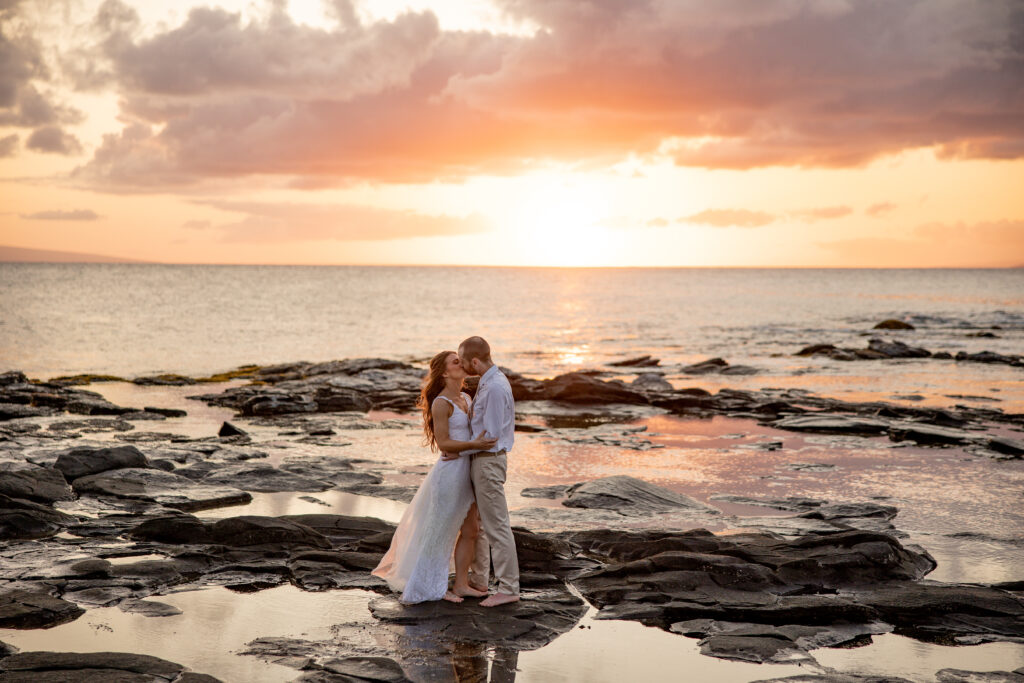 Maui elopement photographer captures bride and groom on rock in ocean after Hawaii beach wedding