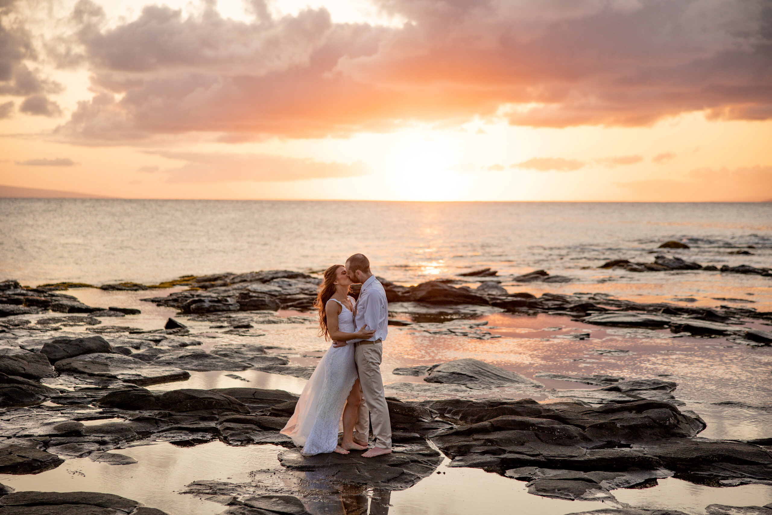 Maui elopement photographer captures bride and groom on rock in ocean after Hawaii beach wedding