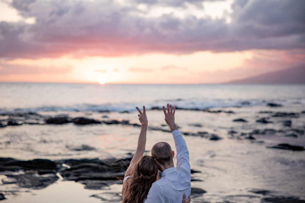 Maui elopement photographer captures bride and groom celebrating with hands in air after Hawaii beach wedding