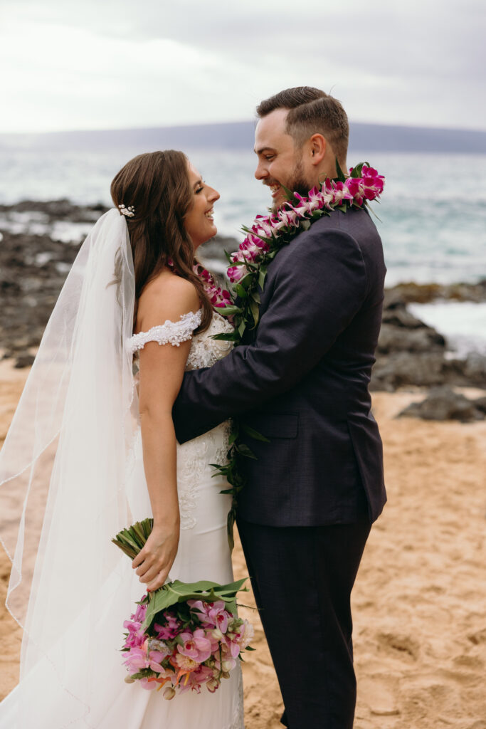 Maui Elopement Photographer captures groom holding bride while she holds bouquet