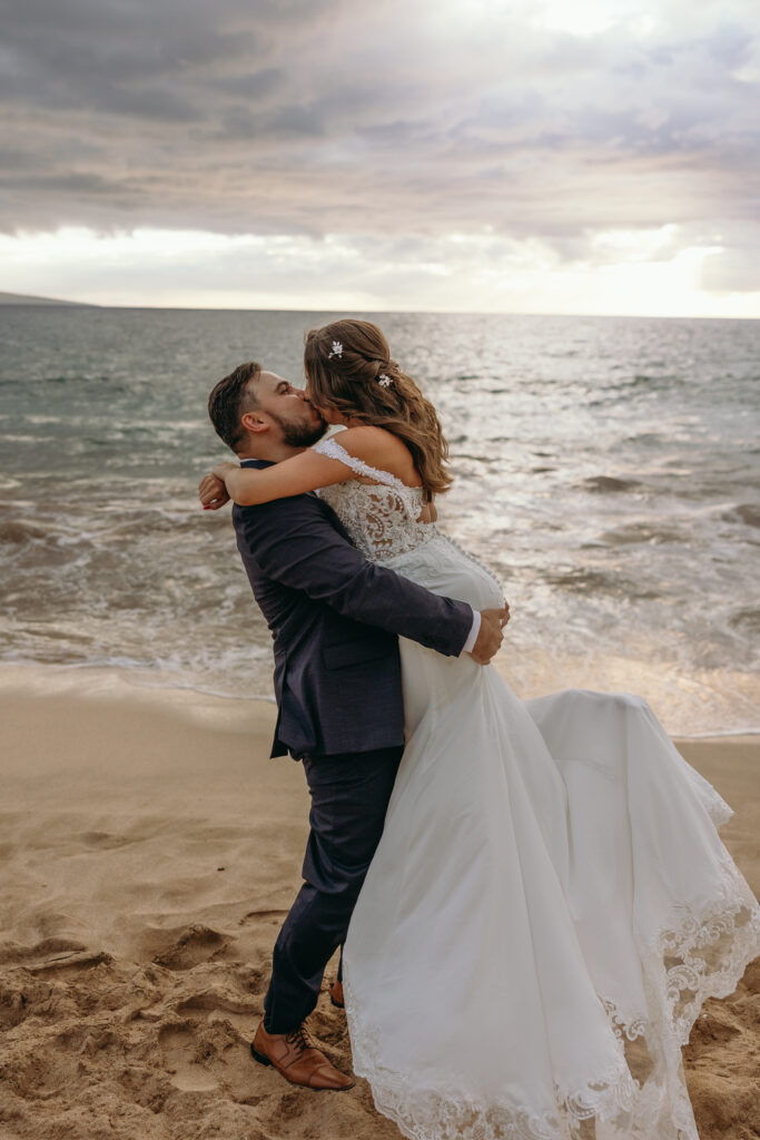 Maui Elopement Photographer captures groom lifting bride and kissing her at sunset