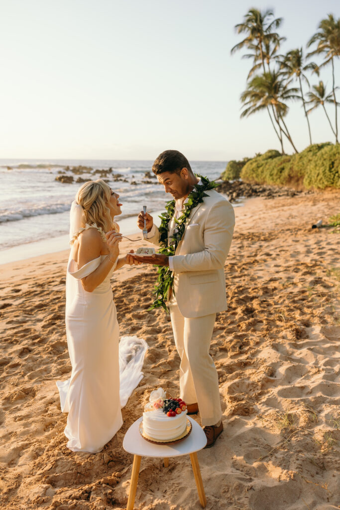 Maui Wedding Photographer captures bride and groom eating cake on the beach