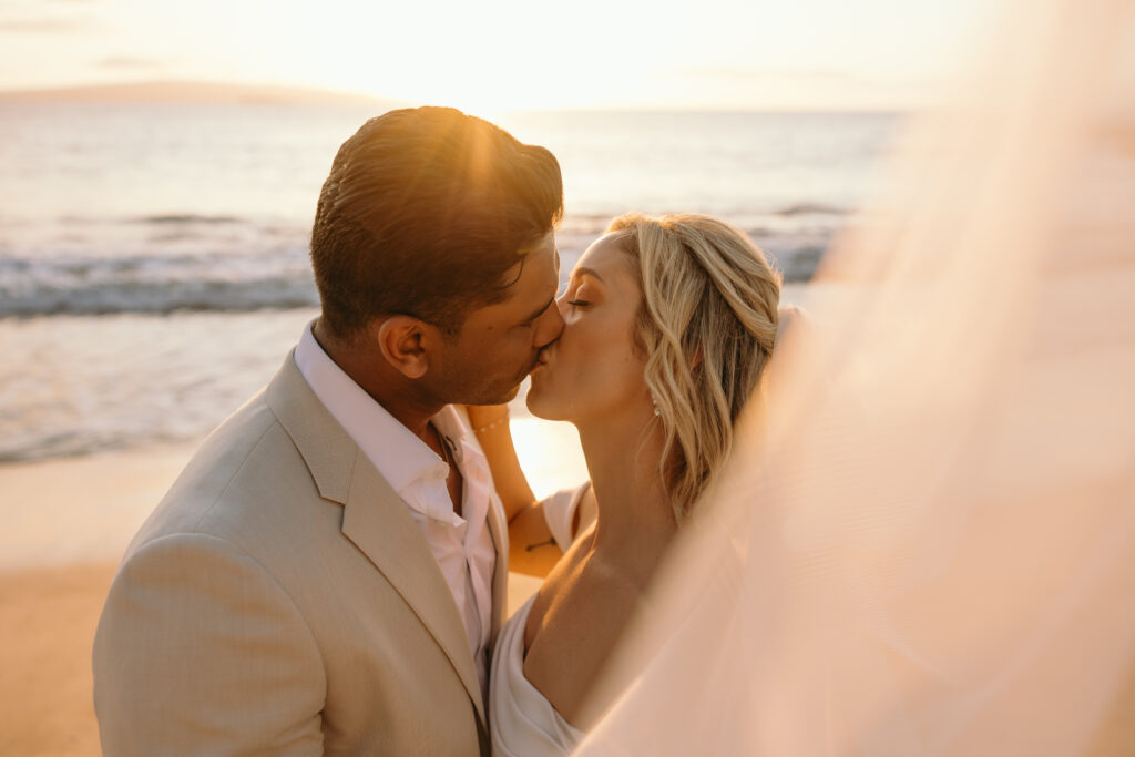 Maui Wedding Photographer captures bride and groom kissing at sunset after Hawaii beach wedding