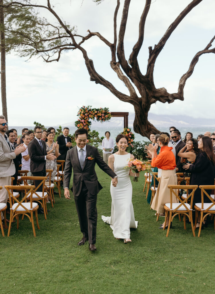 Bride and groom walking out of ceremony hand in hand captured by Maui Elopement Photographer