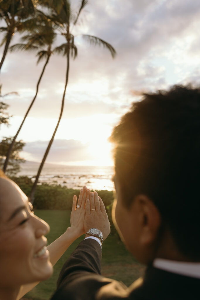 Maui Elopement Photographer captures bride and groom holding up rings after Maui florists created beautiful florals for their hawaii beach wedding