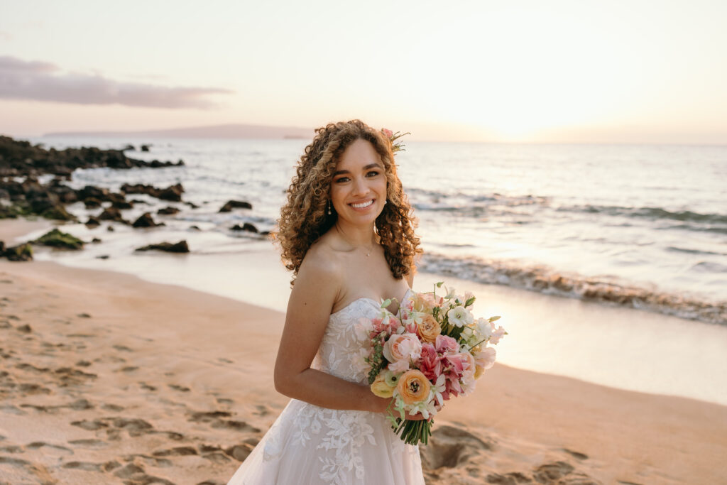 Maui Elopement Photographer captures bride holding bouquet on beach that local Maui florists made for her