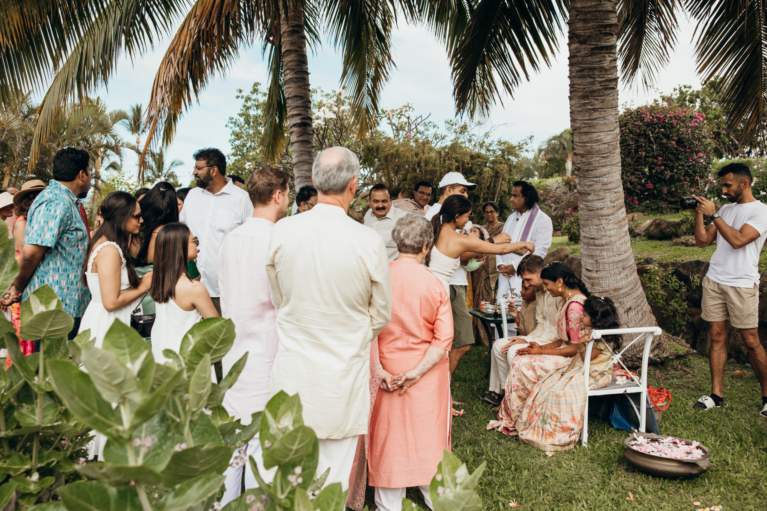 Family and friends gather under palm trees for a traditional ceremony captured by a Maui photographer.