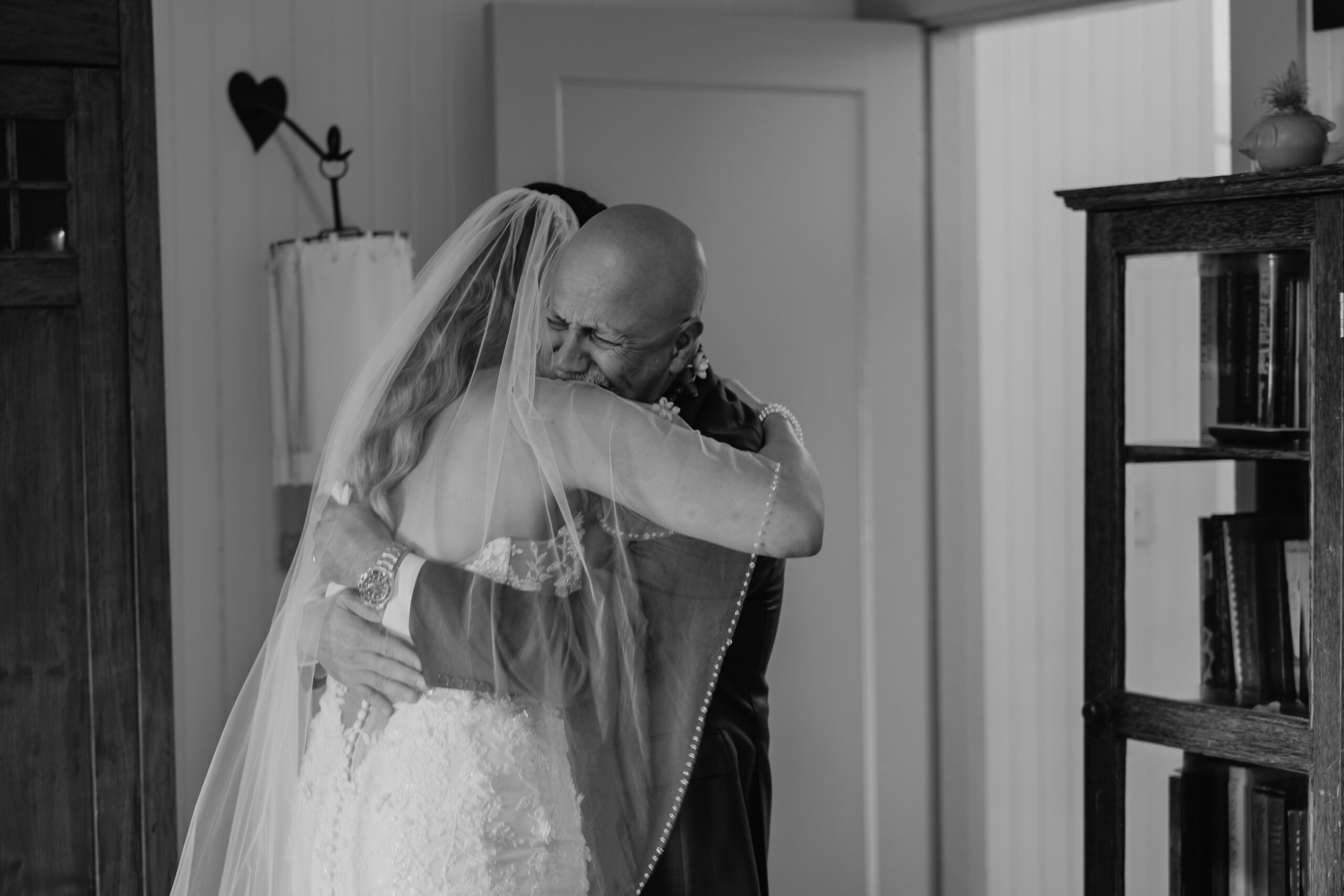 Black and white photo of a heartfelt hug between bride and father, capturing the raw emotion of a first look on a Maui wedding day.