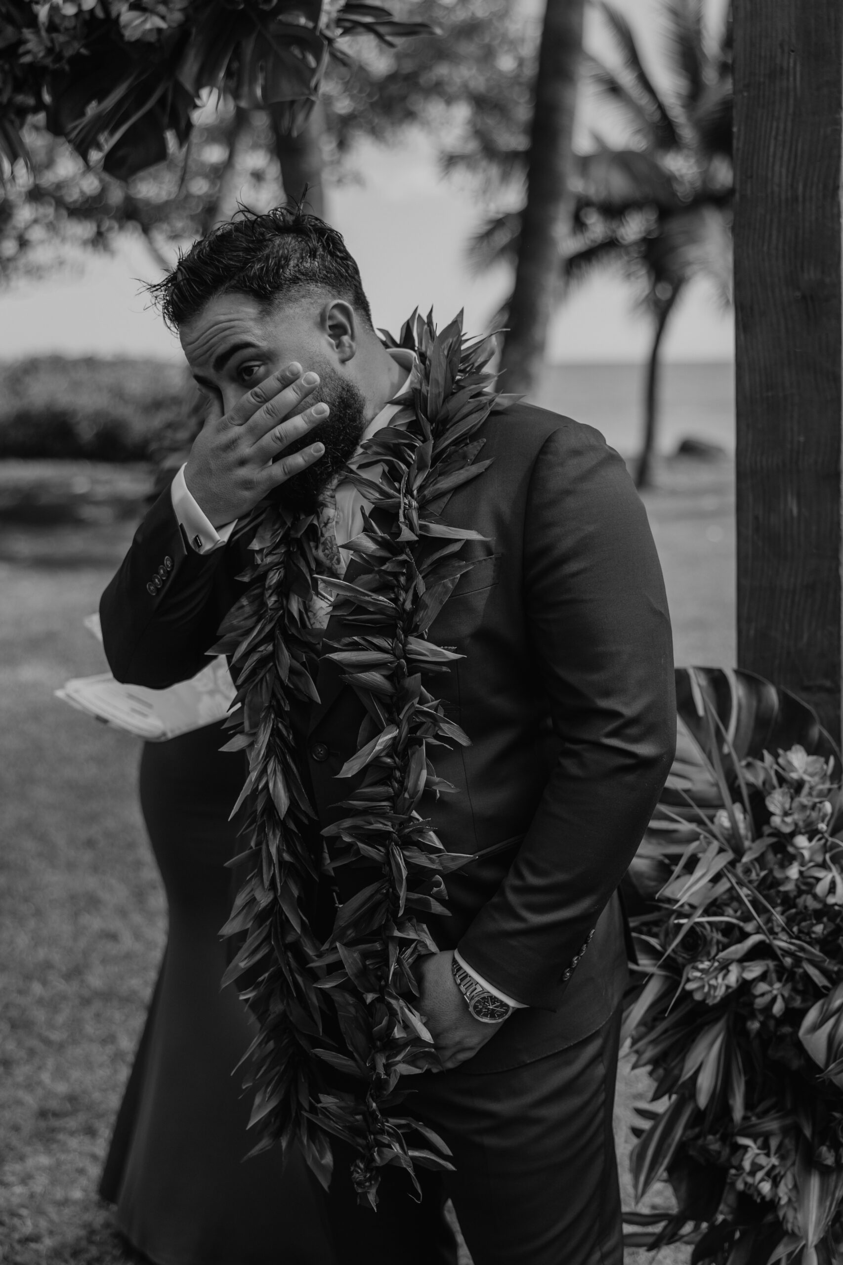 Emotional groom wiping away tears during the ceremony, overwhelmed with joy as he stands beneath the palm trees at a Maui wedding venue.