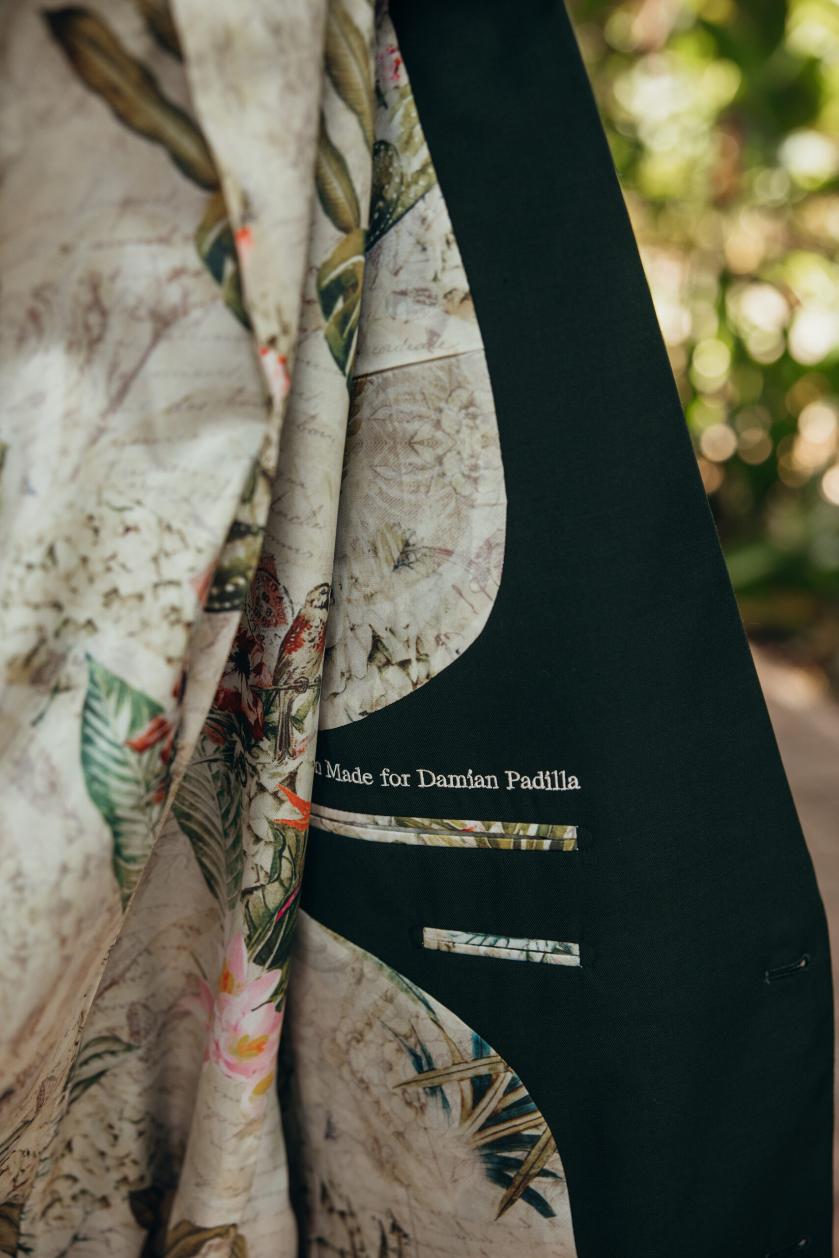 Detailed look at the tropical floral lining of the groom’s custom suit, with embroidery reading “Made for Damian Padilla.”
