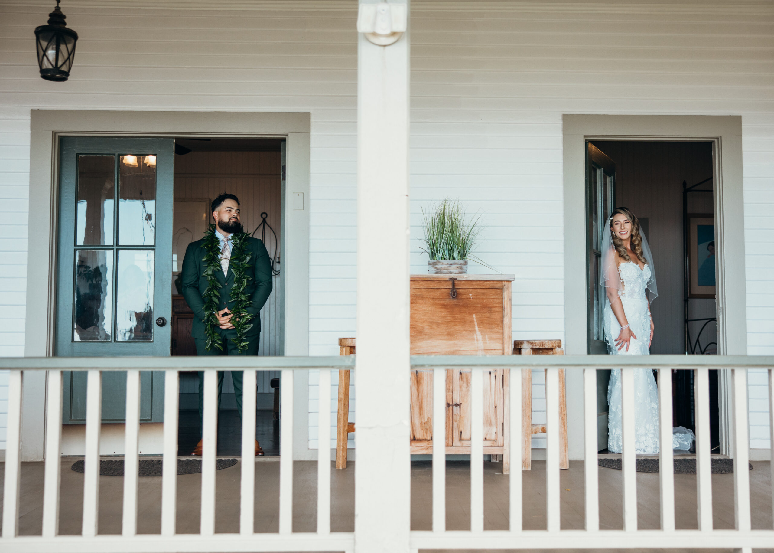 Bride and groom stand on opposite sides of a plantation-style porch during their first look, building anticipation before the big reveal.