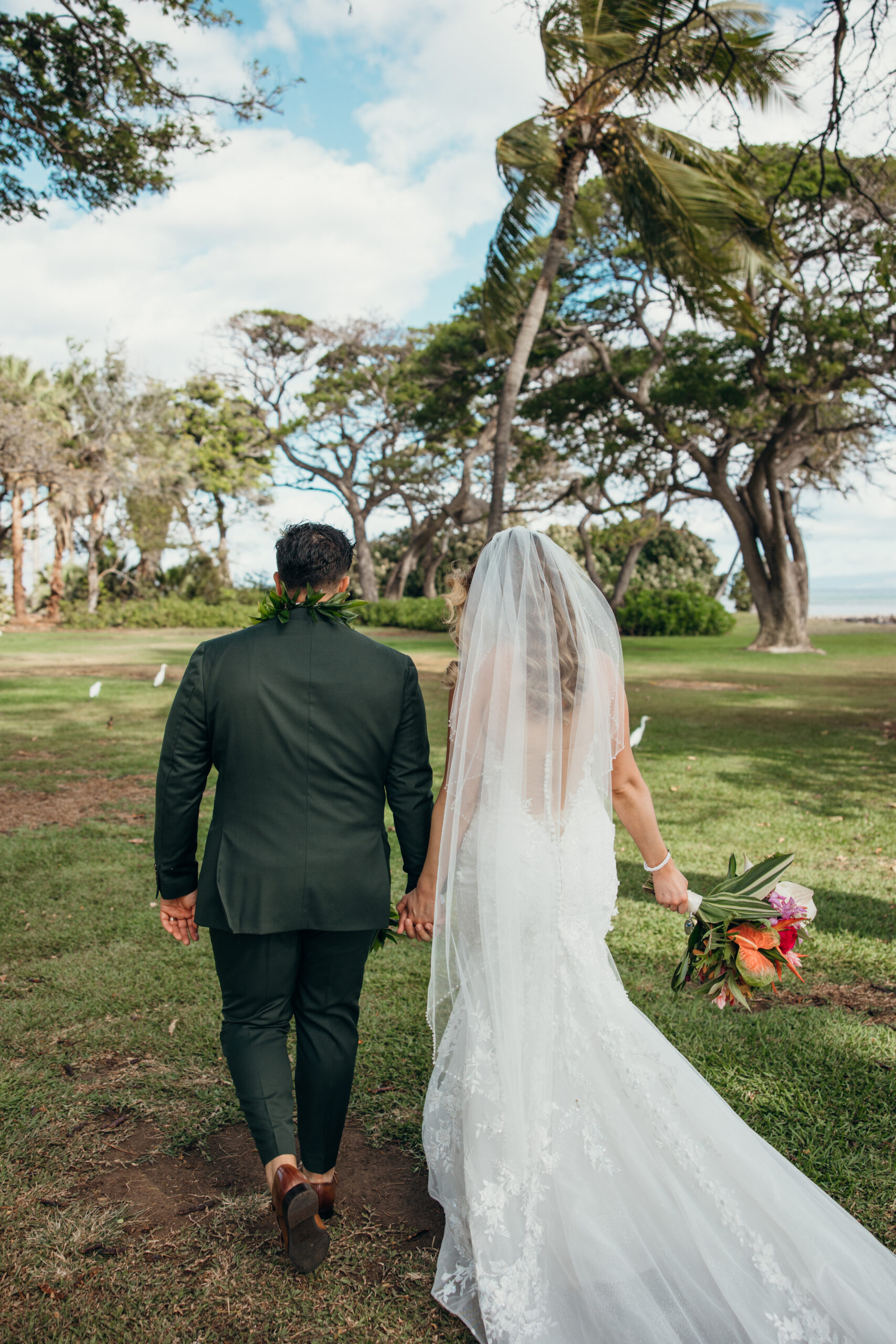 Bride and groom walking away together into the trees, holding hands and bouquet in tow after their ceremony.