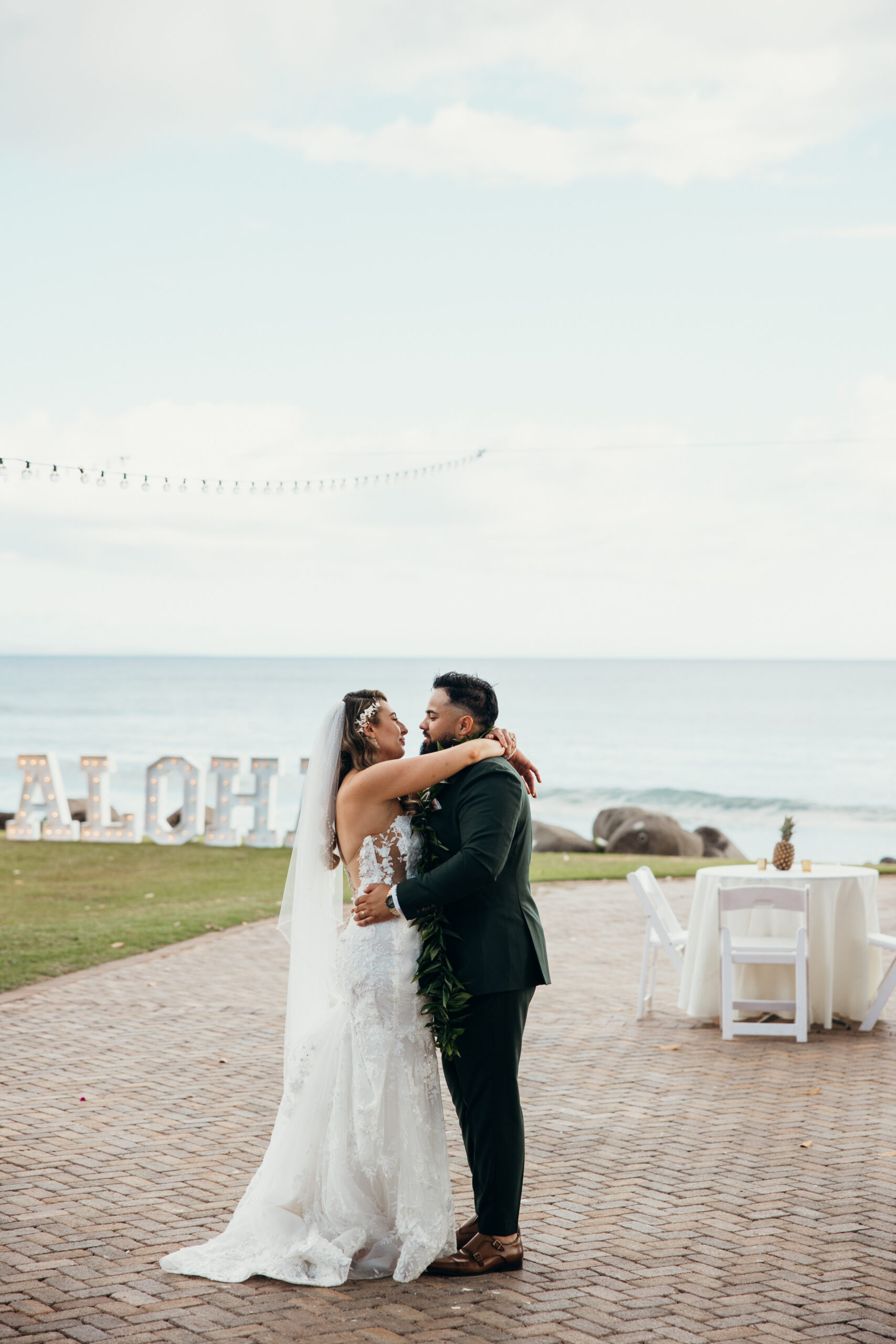 Bride and groom share a private dance near the ocean, framed by palm trees and the soft light of a peaceful Maui evening.