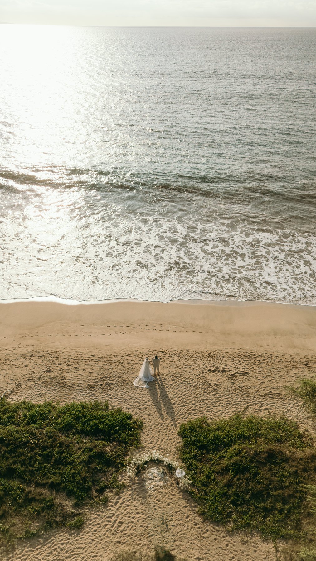 Aerial view of couple standing together on a quiet Makena beach during their Maui elopement day