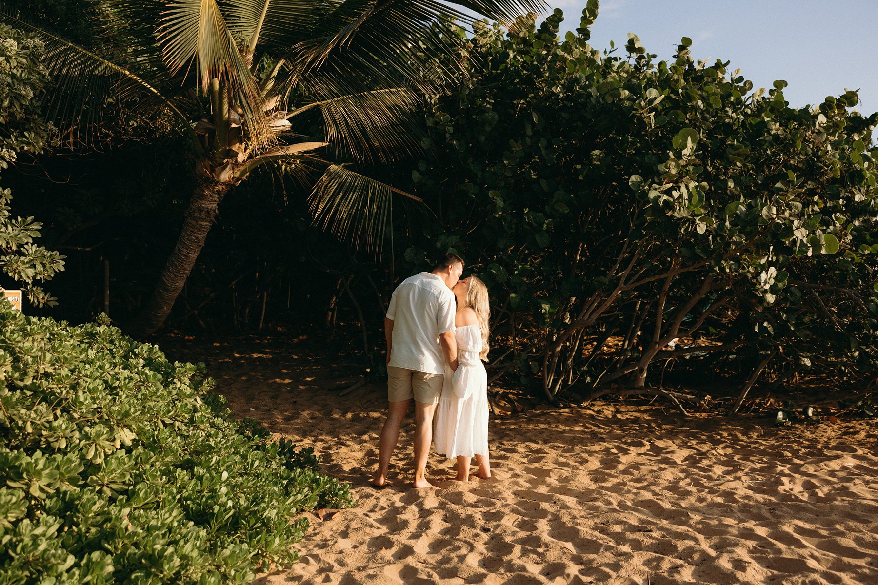 Couple walking toward the ocean at sunset while holding hands during their Maui babymoon maternity session.