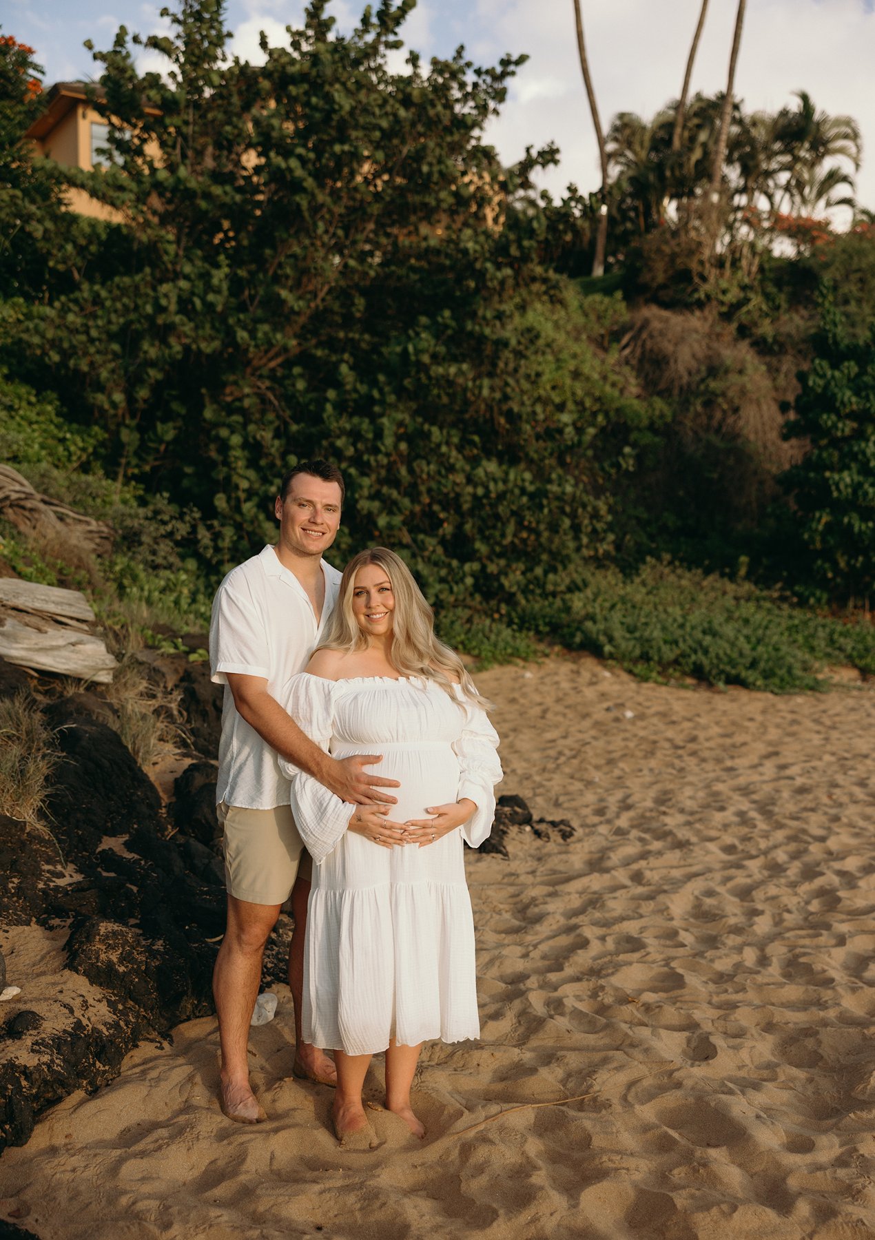 Pregnant woman sitting in shallow water along the shoreline during a beach maternity photoshoot in Maui.