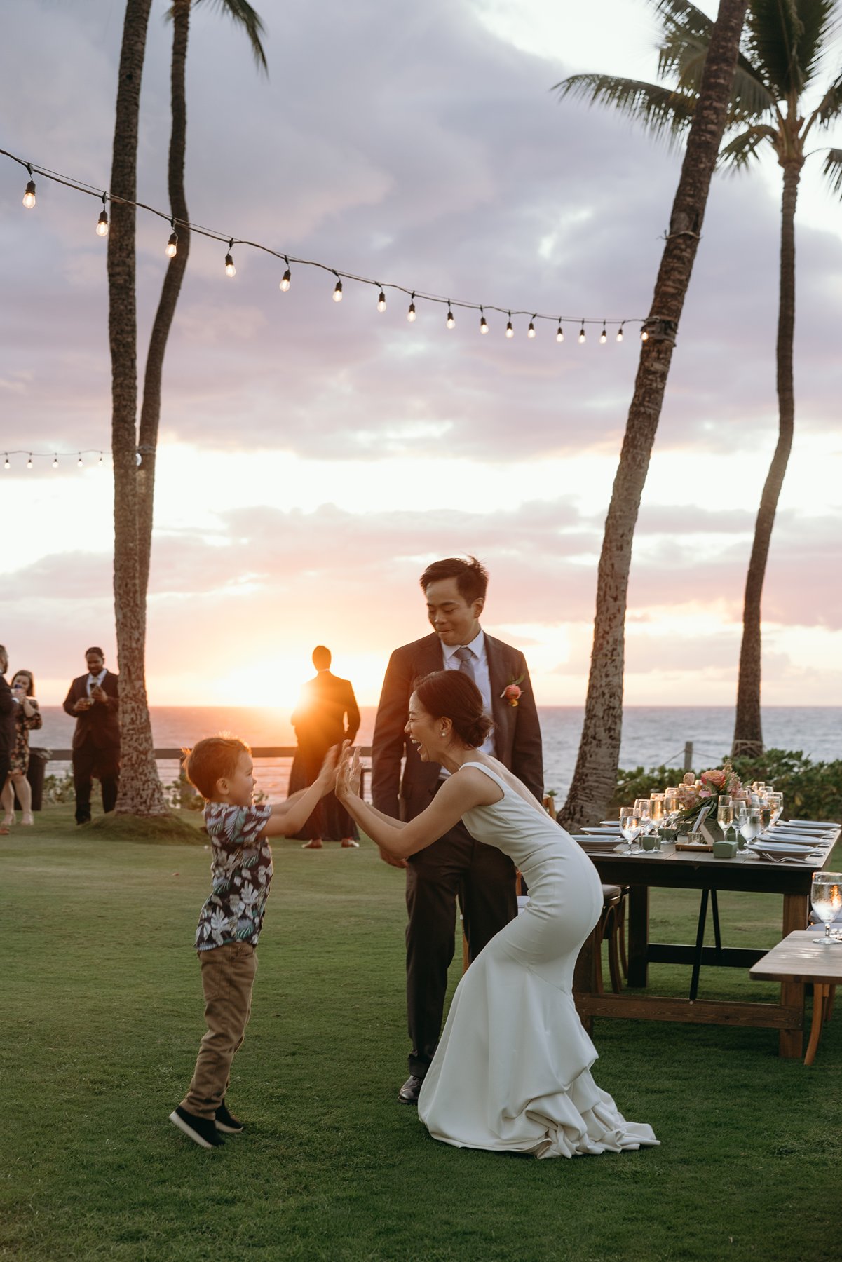 Bride playing with young child during sunset reception on lawn at resort wedding venue