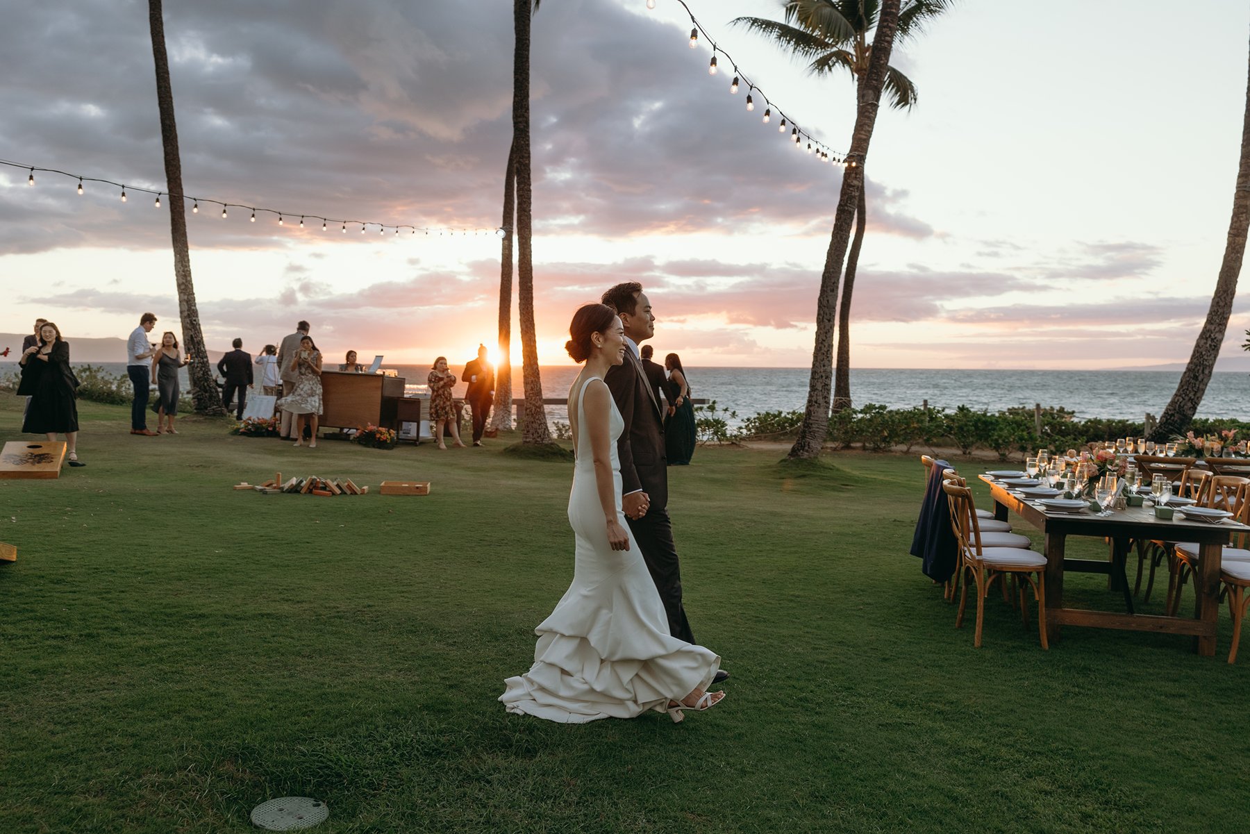 Bride and groom walking together during golden hour at Maui resort wedding venue with ocean view reception setup