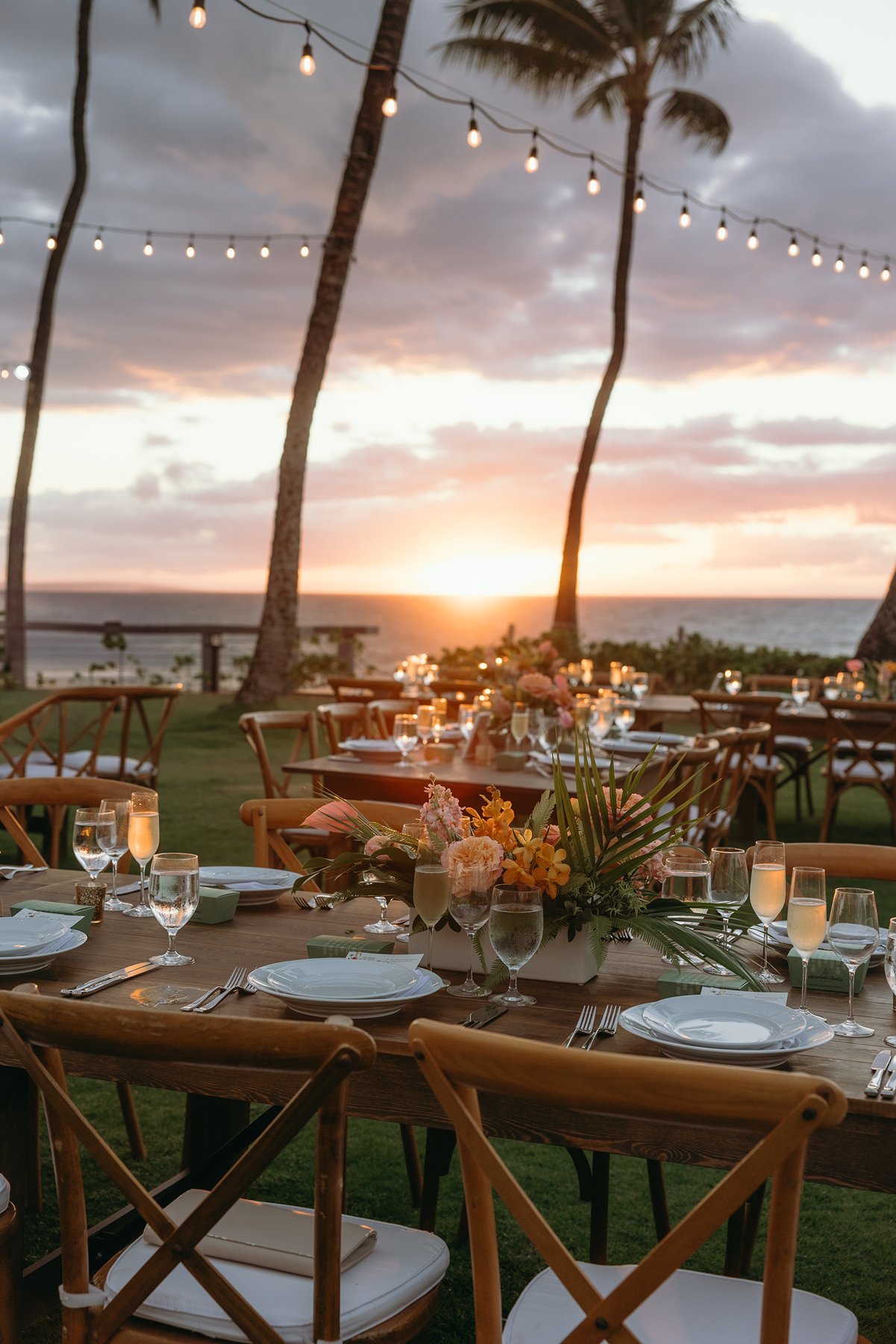 Reception table setup with candles, florals, and ocean sunset view at Maui resort wedding venue