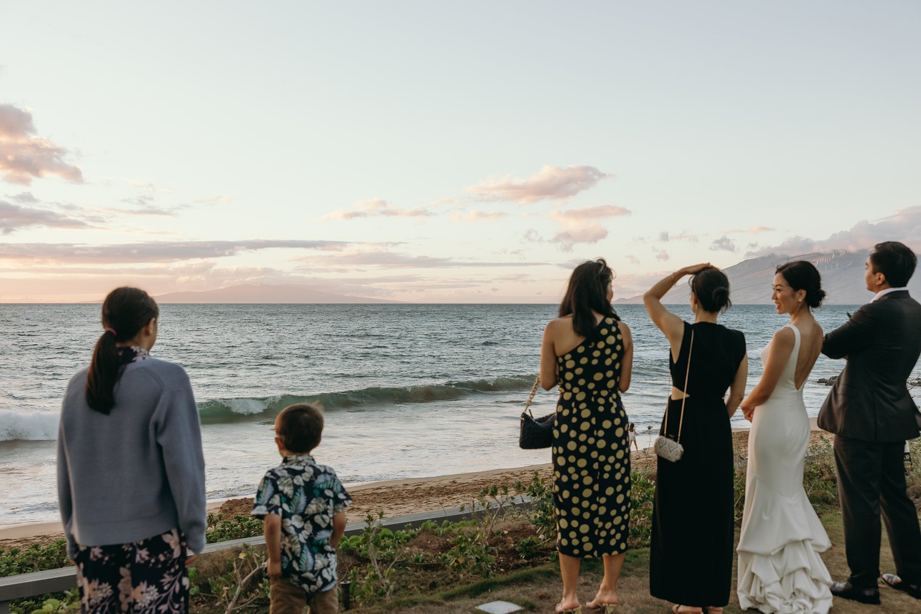 Wedding guests gathered along the beach watching sunset during Hawaii wedding celebration