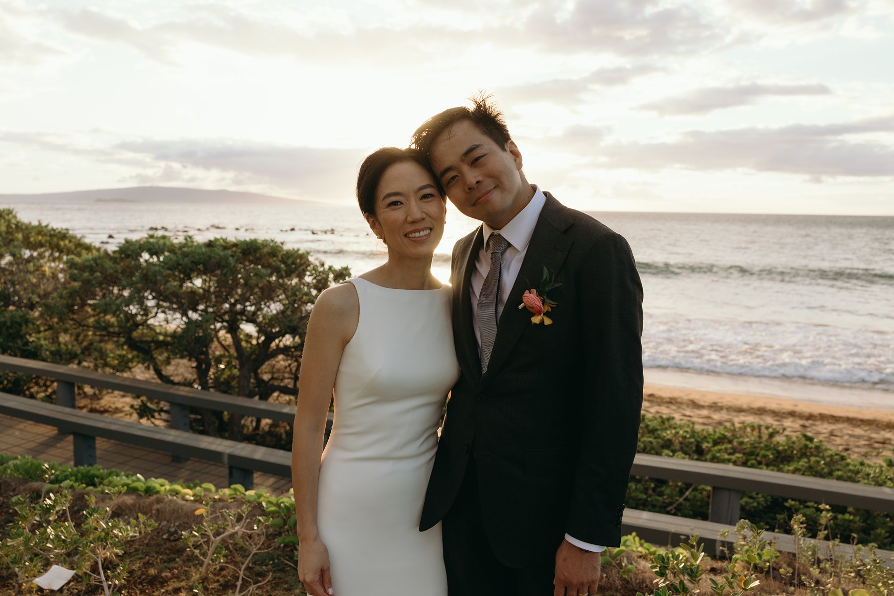 Bride and groom smiling together by the ocean at sunset in Maui