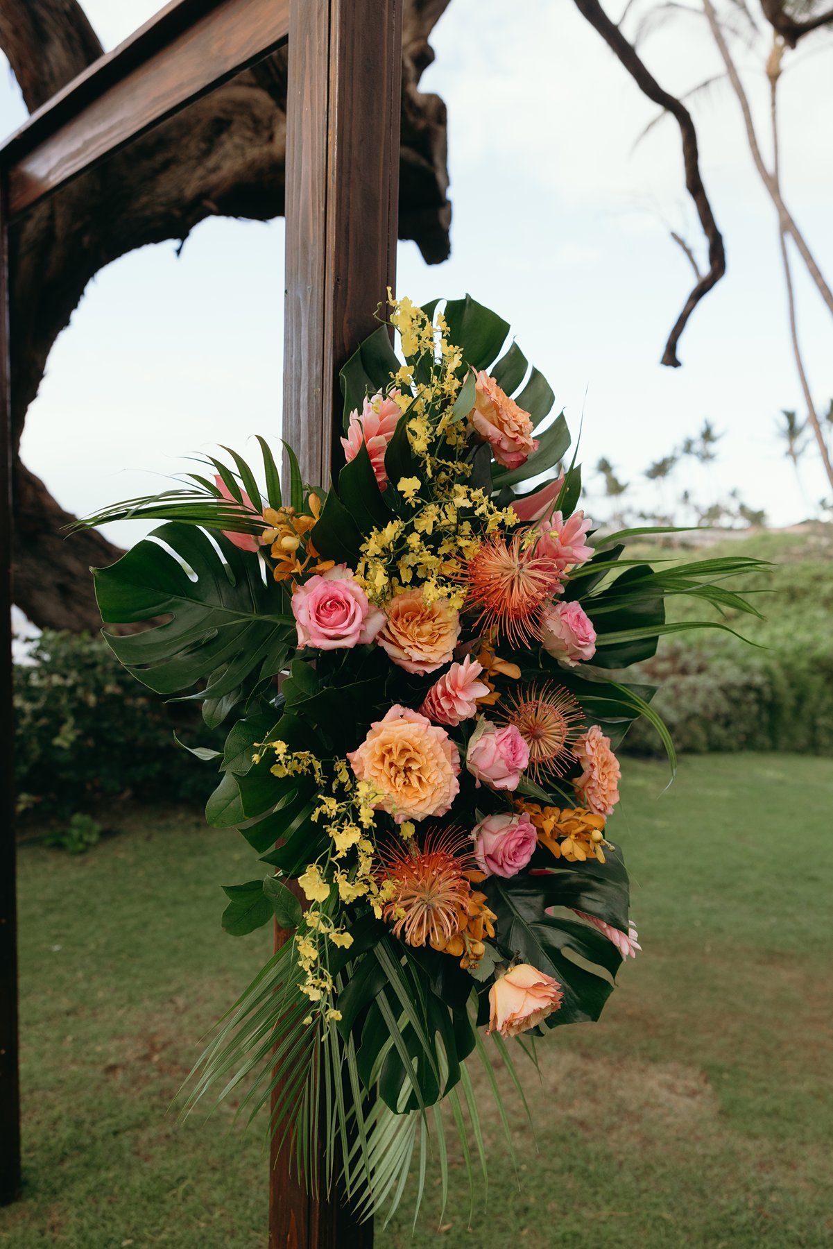 Tropical floral arrangement on wooden ceremony arch at Maui resort wedding venue