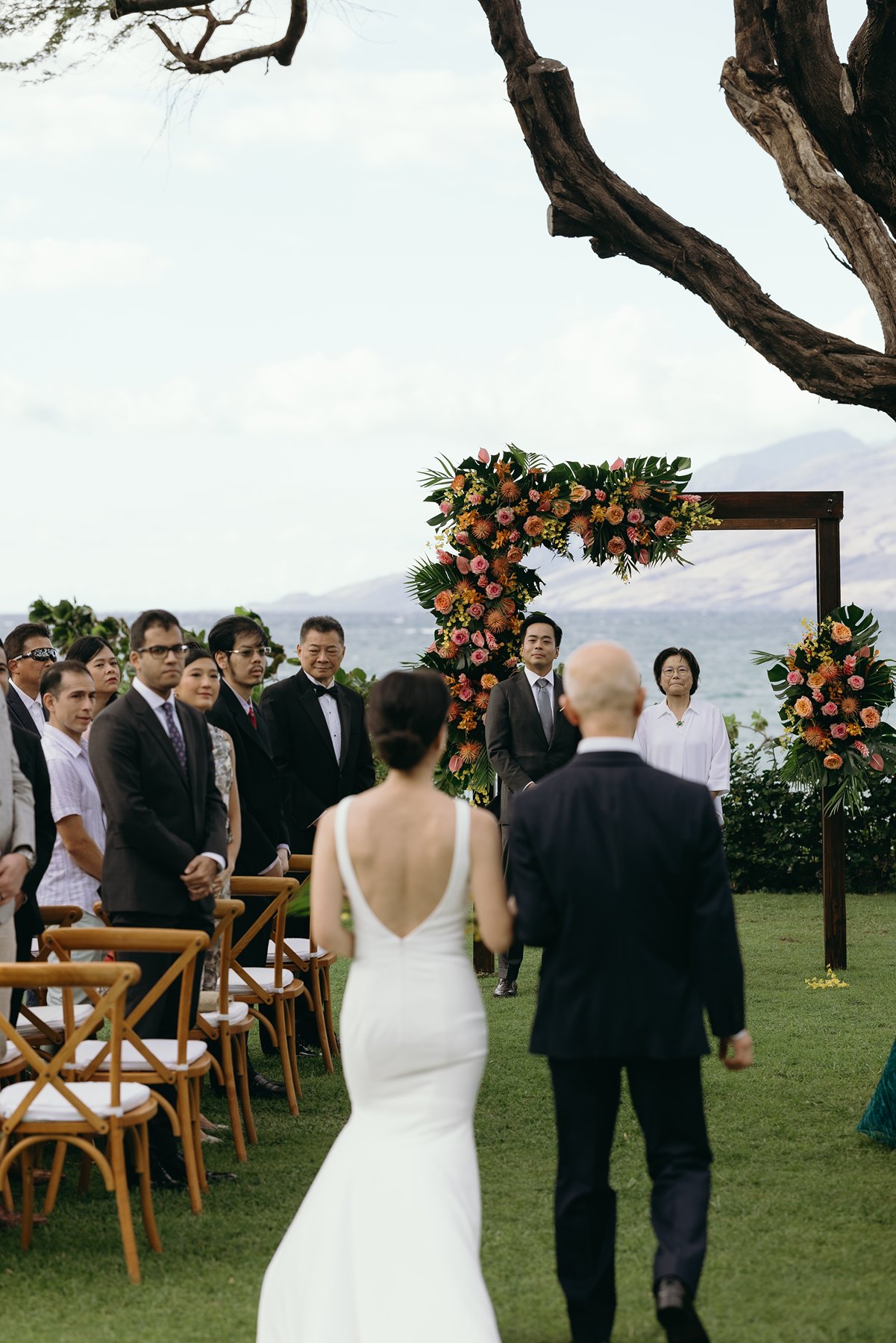 Bride walking down aisle with parent toward oceanfront ceremony setup at Maui resort wedding venue