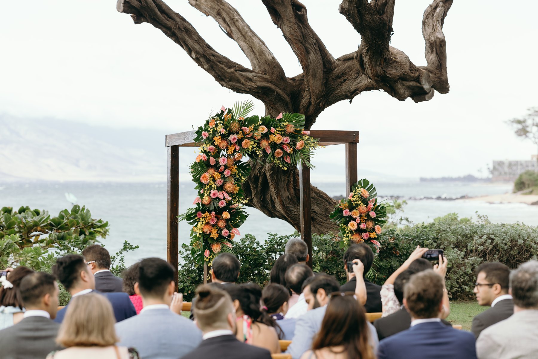 Floral ceremony arch with tropical flowers overlooking ocean at Maui resort wedding venue