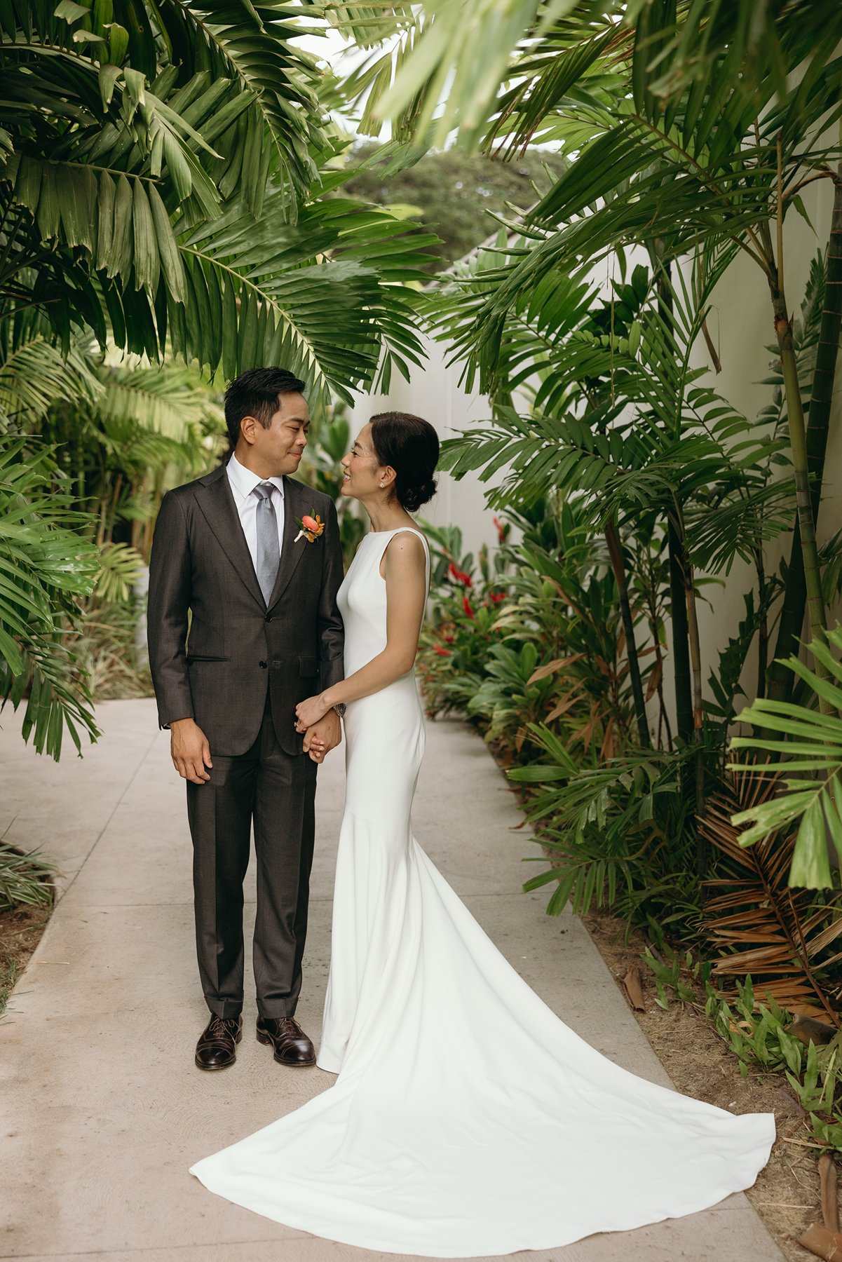 Bride and groom standing together in lush tropical garden pathway at Hawaii resort wedding venue