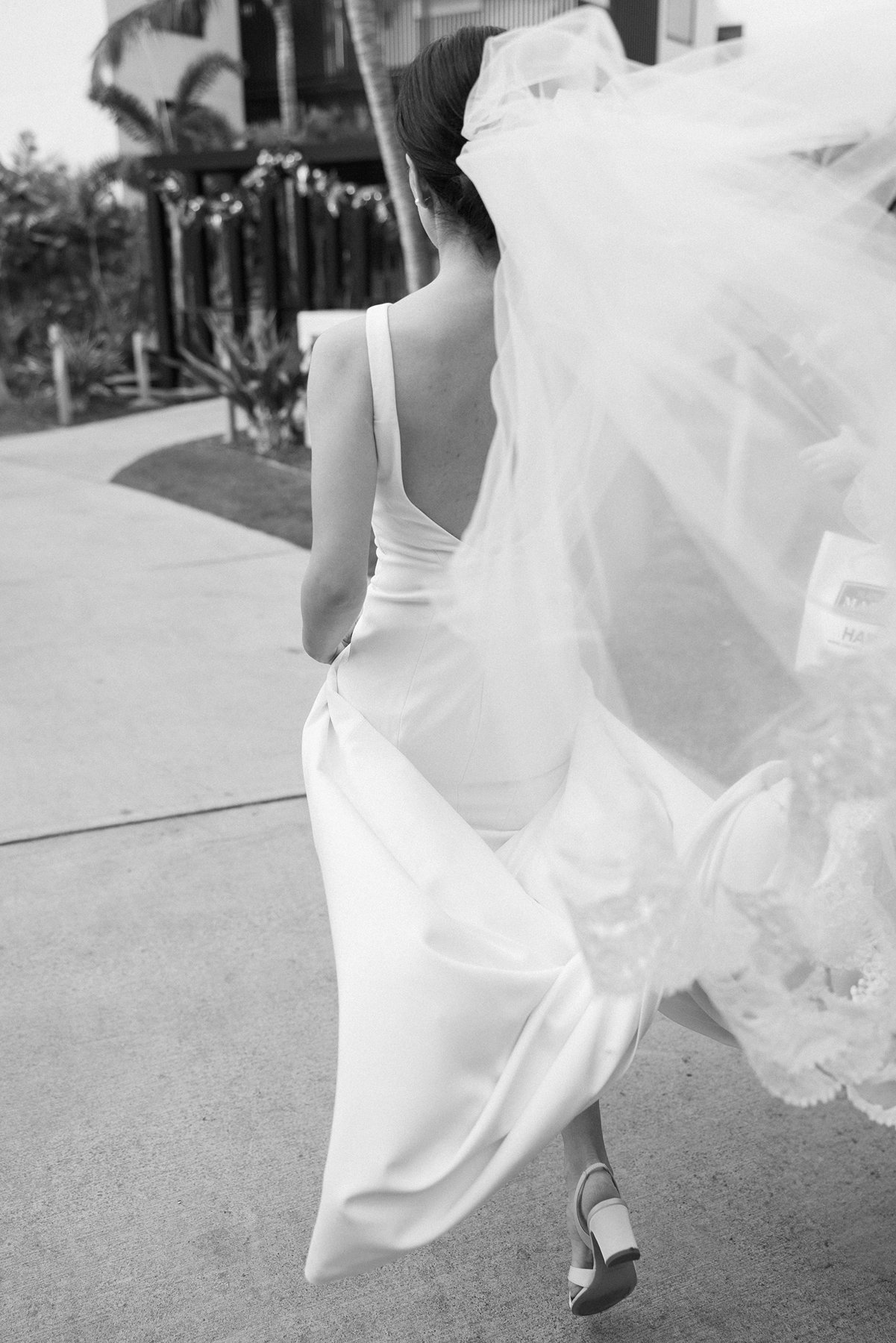 Bride walking with flowing veil in black and white at Hawaii wedding
