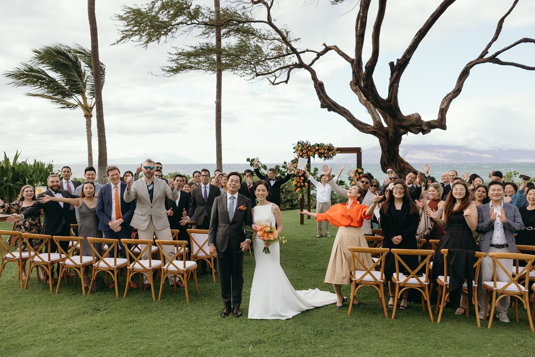 Bride and groom standing with guests cheering after ceremony at oceanfront resort wedding venue in Maui