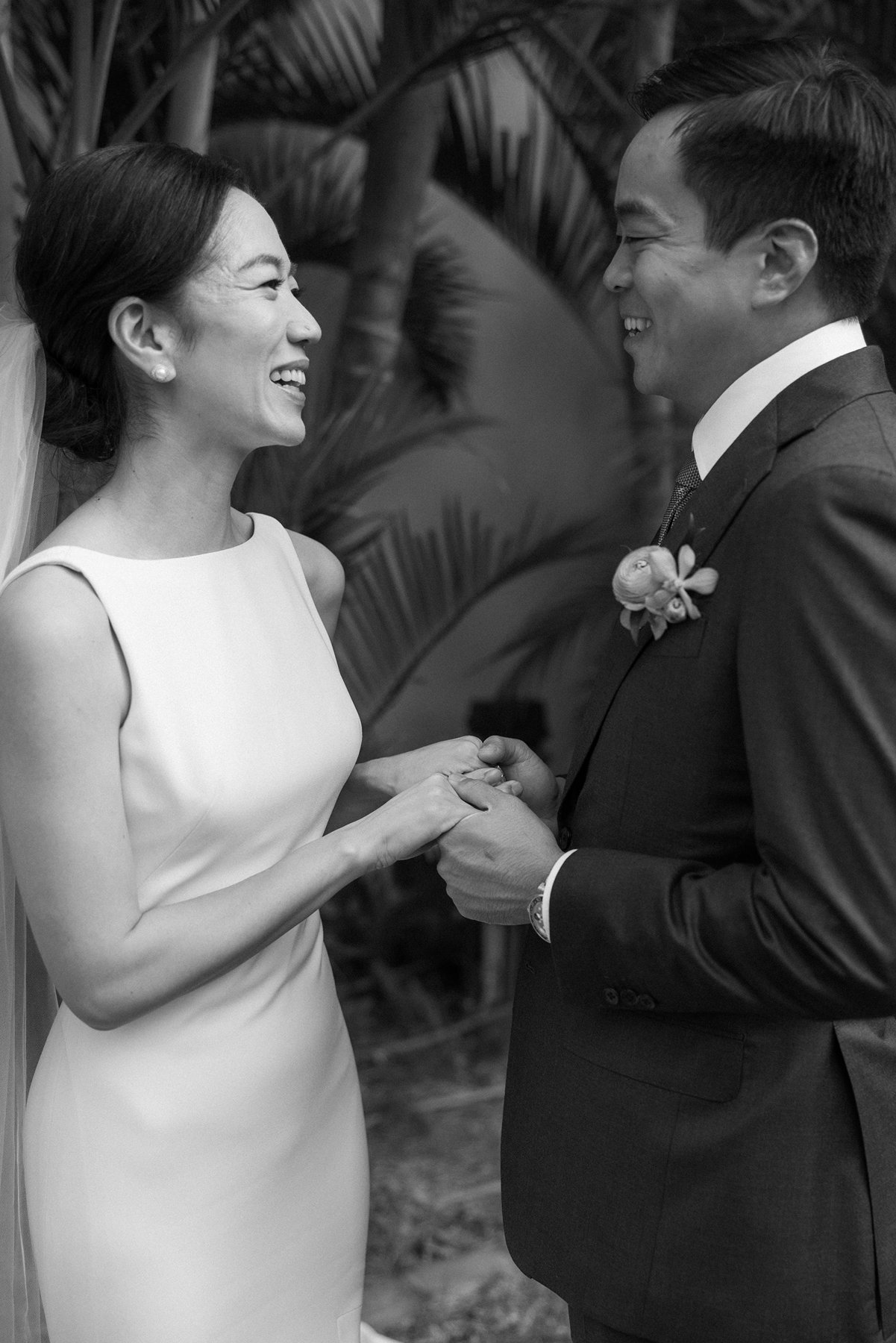 Black and white photo of bride and groom smiling and holding hands during wedding day