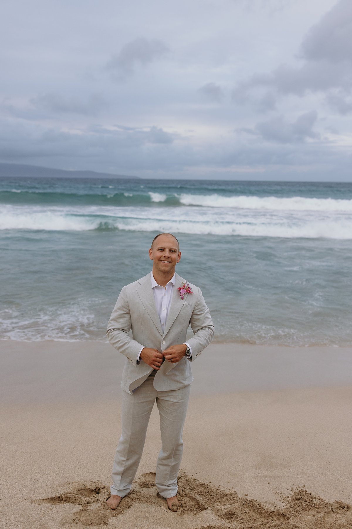 Groom standing barefoot at the shoreline before the ceremony, smiling at the ocean as he prepares to elope in Maui.