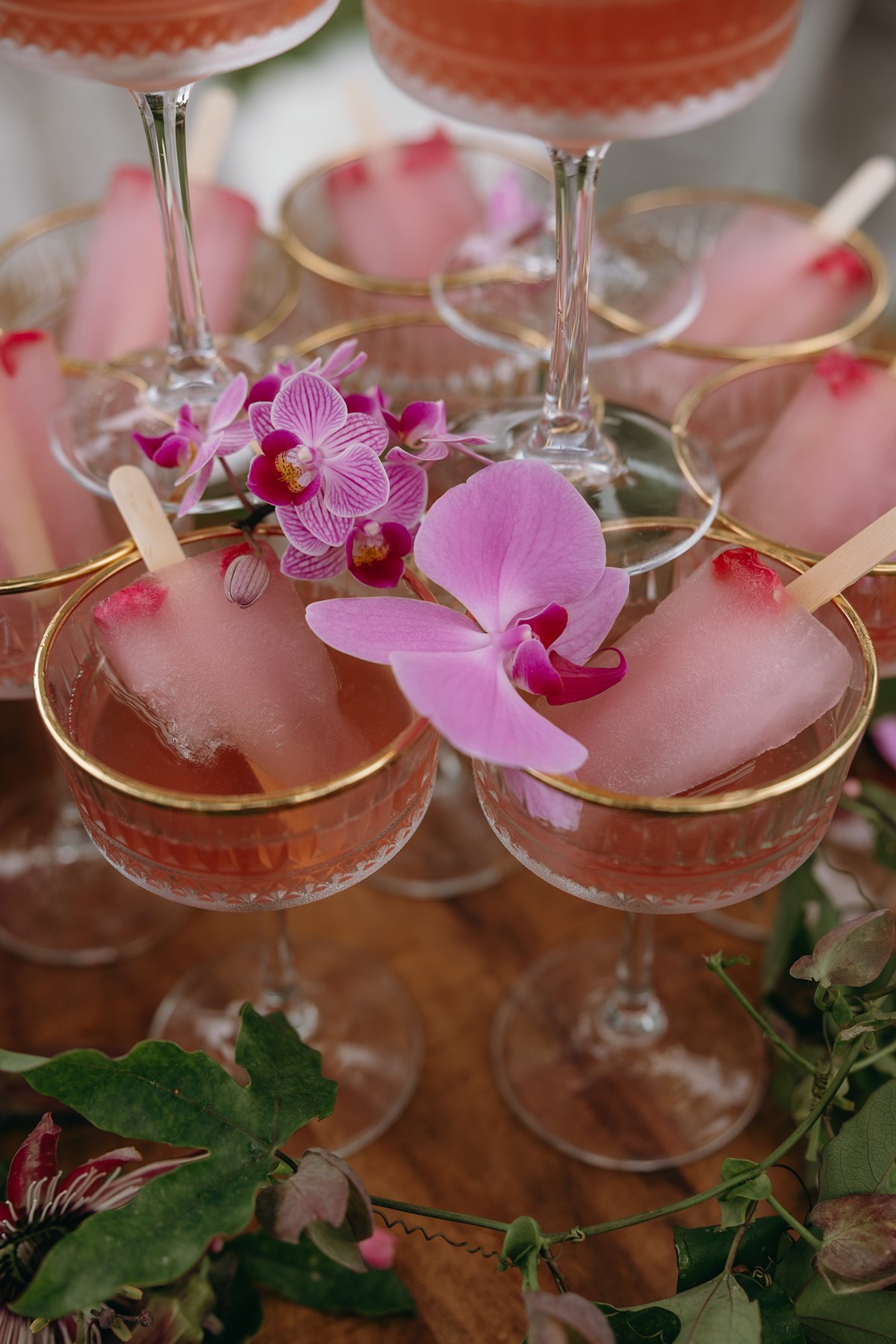 Coupe glasses filled with pink champagne and garnished with orchids during a celebration after the couple decided to elope in Maui.