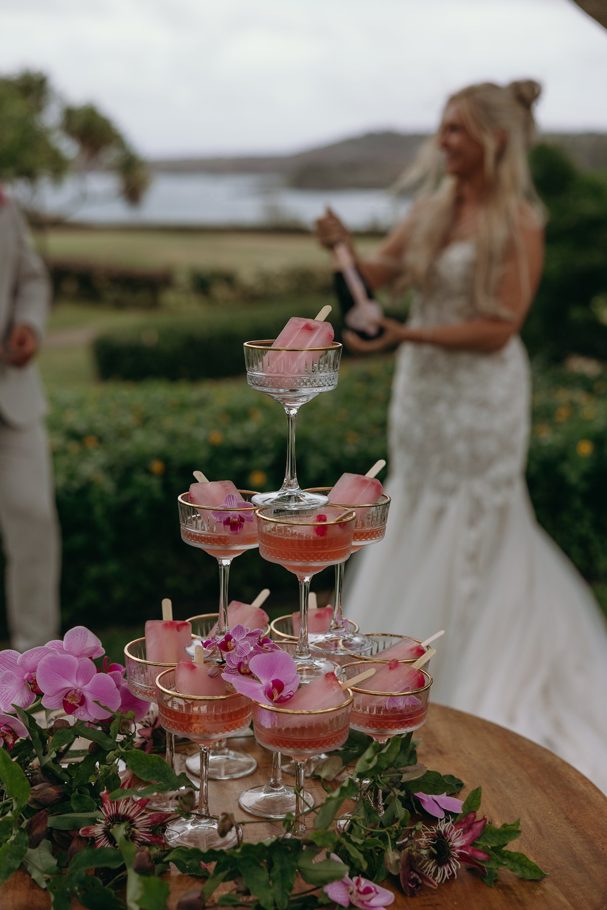 Close-up of a champagne tower decorated with orchids and tropical blooms, styled for a Maui beach elopement celebration.