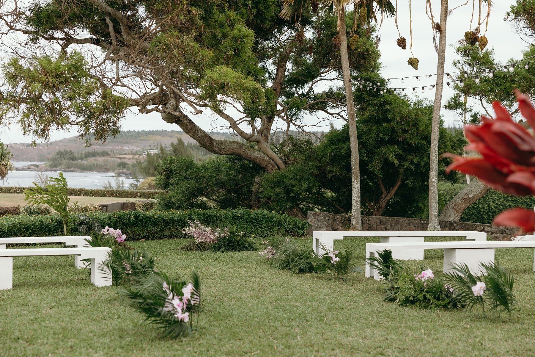 Intimate garden ceremony setup with white benches and tropical greenery arranged for a couple about to elope in Maui.