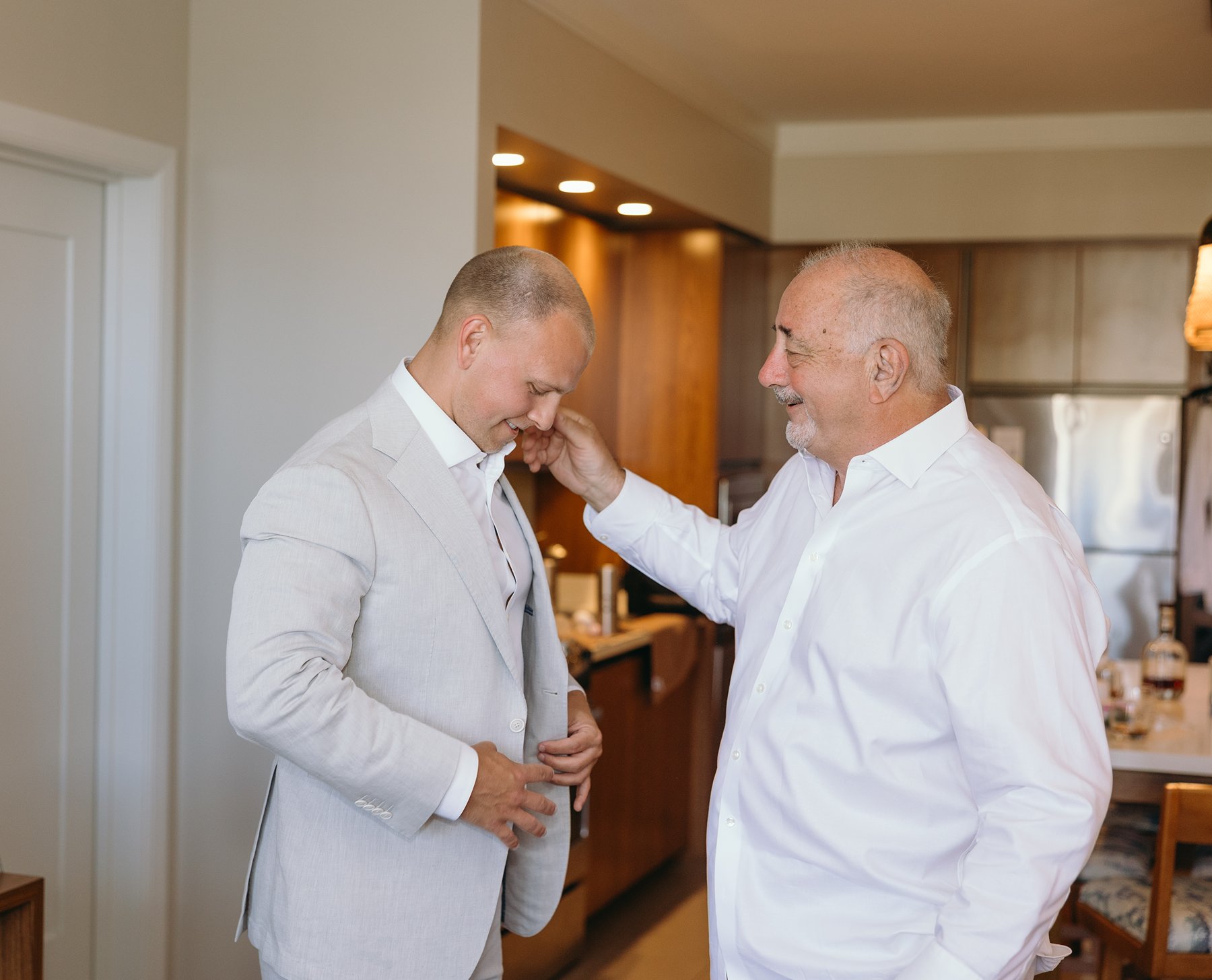 Father adjusting the groom’s jacket in a quiet getting-ready moment before the couple elope in Maui.