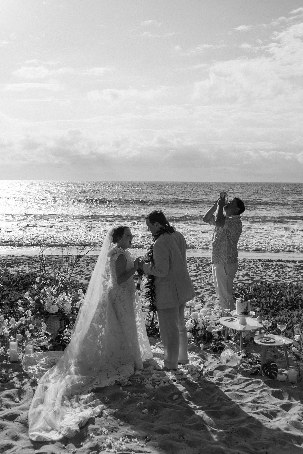 Black and white photo of a couple exchanging leis during their Maui beach ceremony captured in elopement photography.