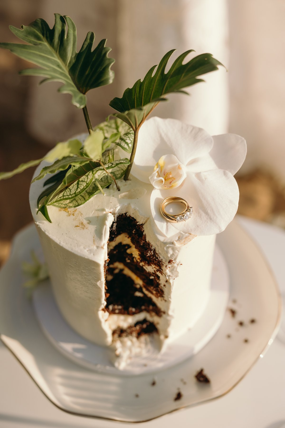 Small tropical wedding cake topped with a white orchid and wedding rings during an intimate elopement photography celebration.