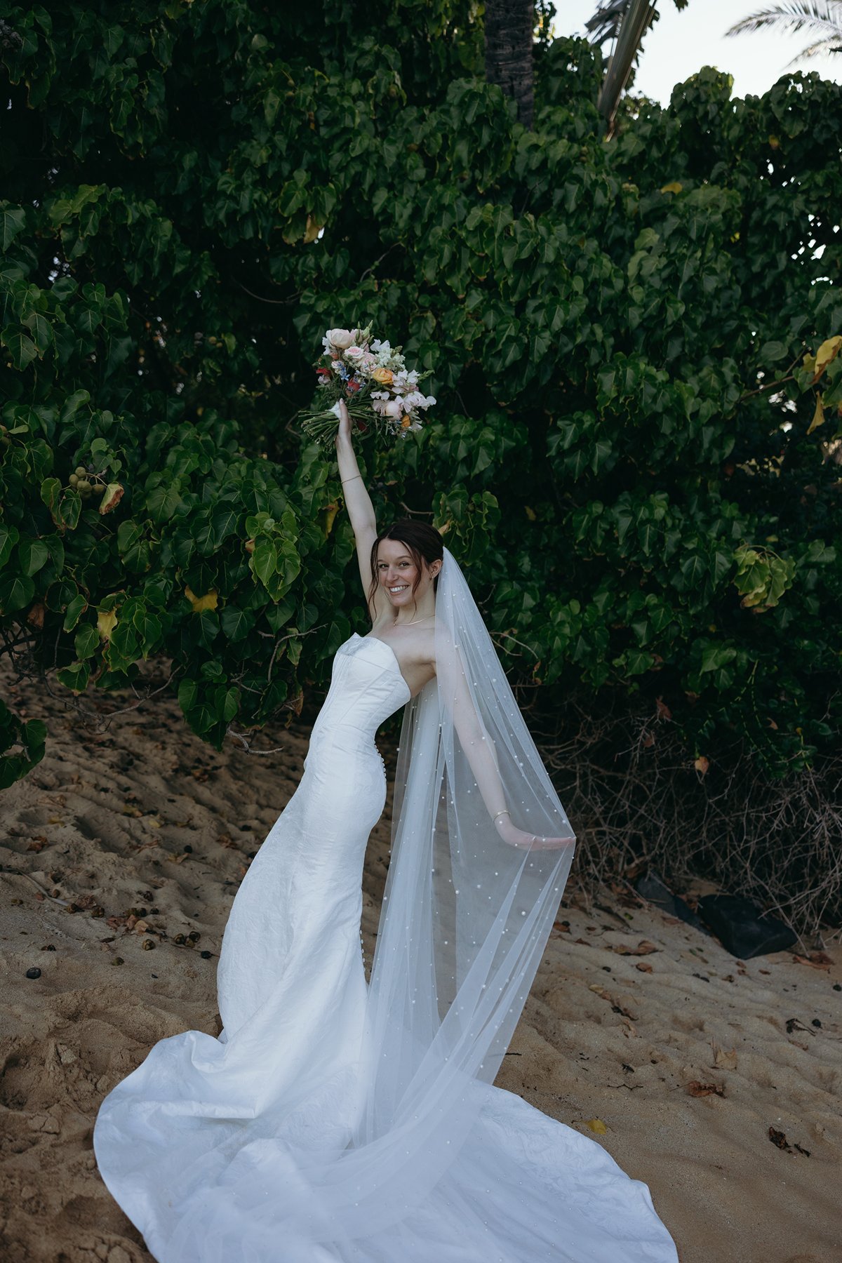 Bride celebrating with bouquet in the air during joyful wedding sneak peek photos