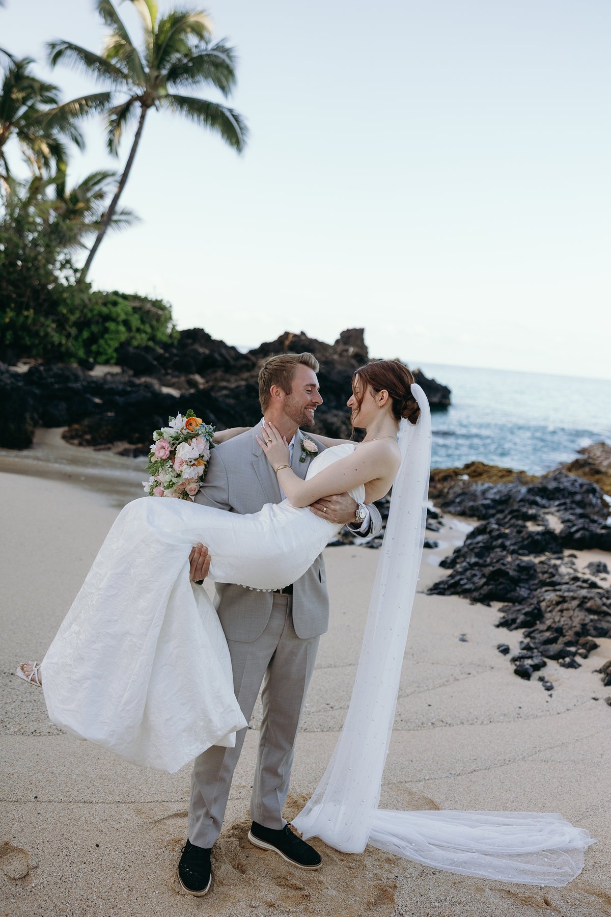 Groom lifting bride on a tropical beach during romantic wedding sneak peek photos