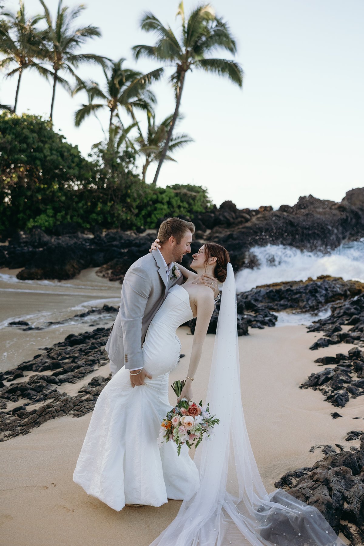 Bride and groom sharing a romantic dip kiss on a tropical beach during wedding sneak peek photos
