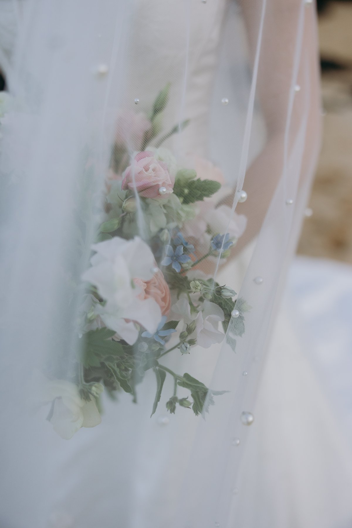 Close-up of bridal bouquet through veil in dreamy wedding detail sneak peek photos