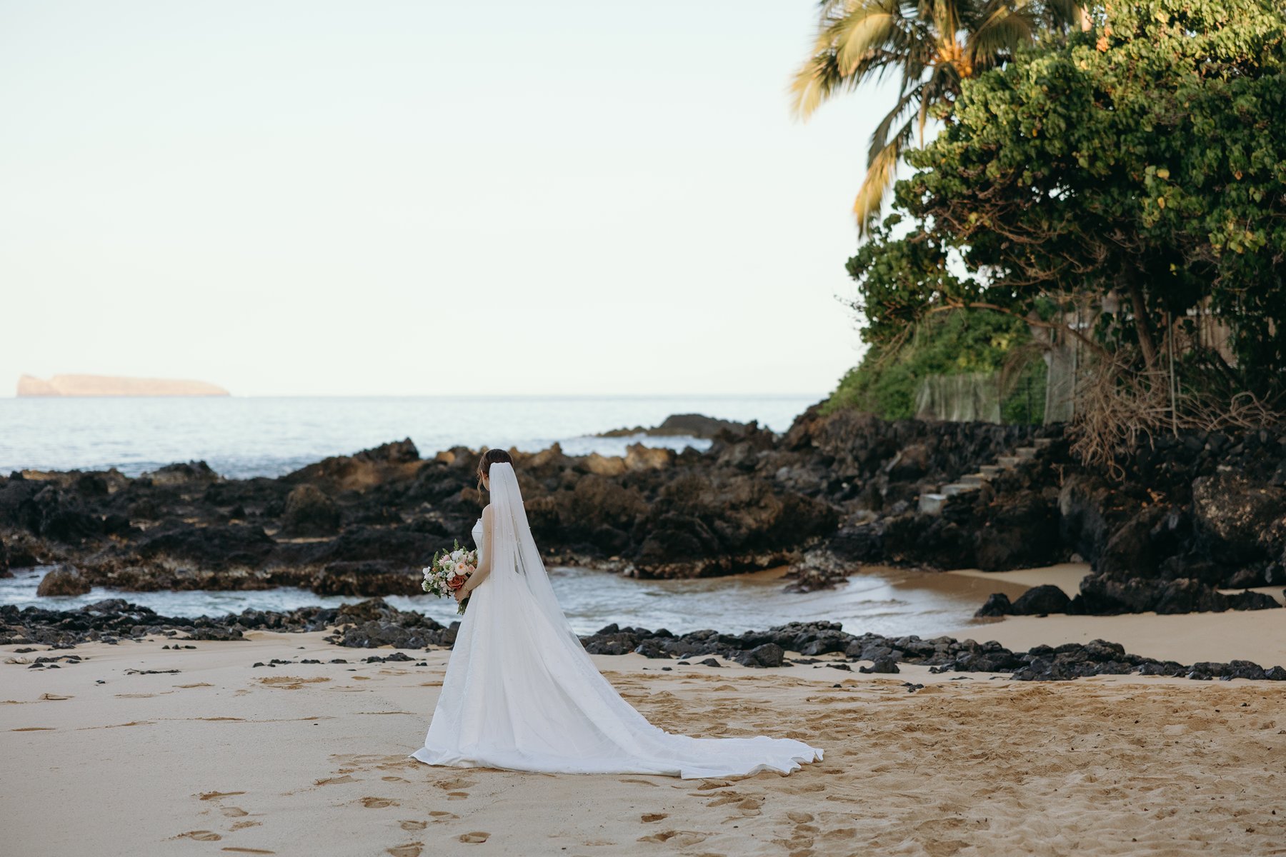 Bride walking along Maui shoreline in flowing veil during wedding sneak peek photos