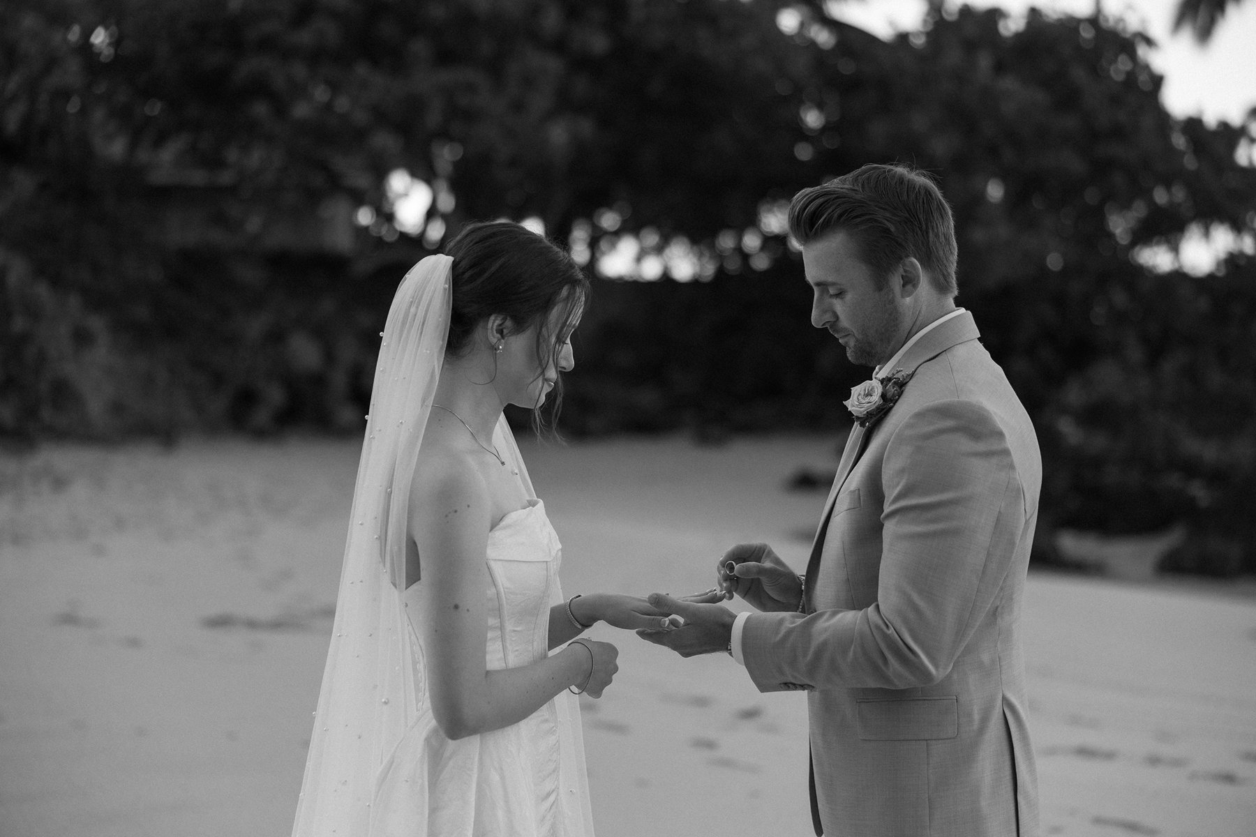 Black and white sneak peek photos of bride and groom exchanging rings during ceremony