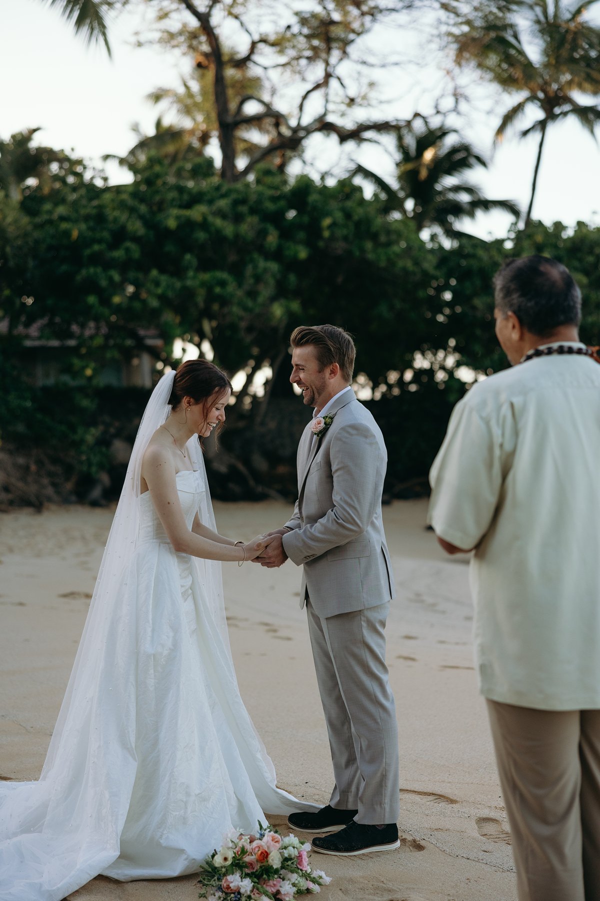 Bride and groom holding hands during beach ceremony with officiant in wedding sneak peek photos