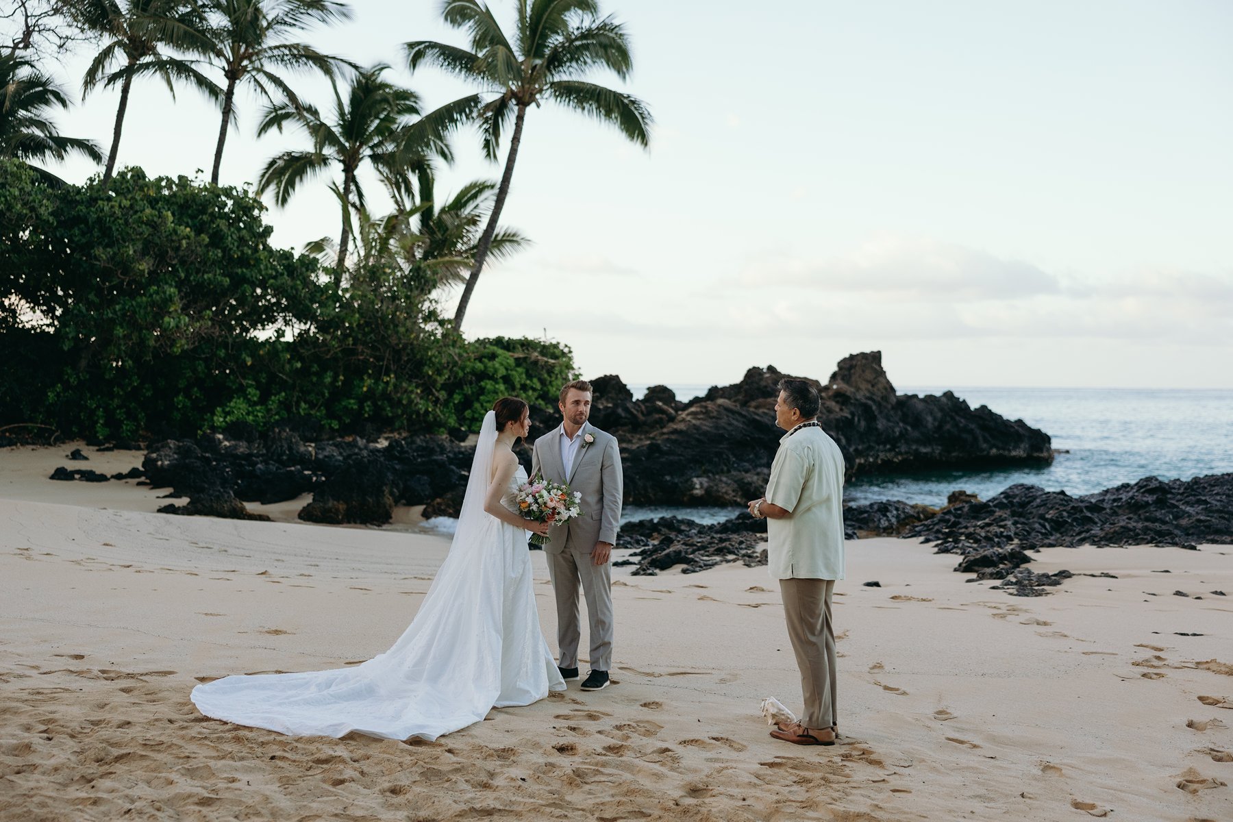 Beach wedding ceremony with officiant and couple exchanging vows in Maui sneak peek photos