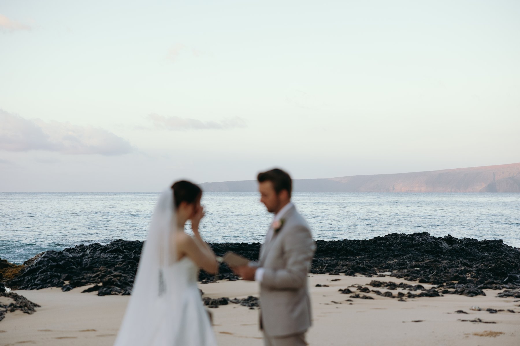 Emotional moment during beach vows with bride and groom in soft focus sneak peek photos