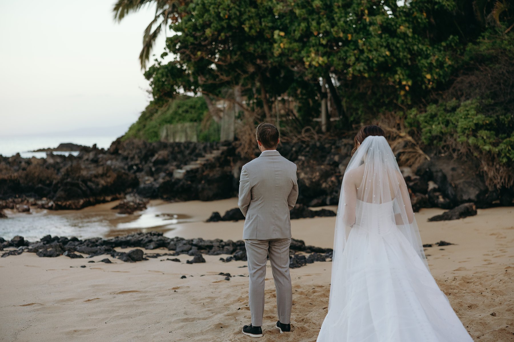 Bride and groom standing side by side facing the ocean during beach ceremony in Maui sneak peek photos
